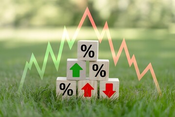 Financial growth and decline represented by percentage blocks and stock market graph overlayed on a natural green grass background symbolizing economic fluctuations and investment trends
