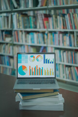 A laptop screen displaying a graph and a book placed on the table in the library, representing a business concept.	