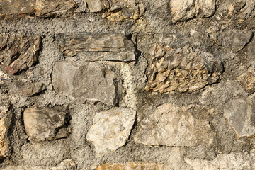 Detailed close-up of a stone wall built with natural rocks embedded in concrete mortar, showcasing rugged texture and structure.