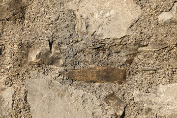 Rough stone wall built with irregular rocks and gray concrete mortar, ideal for backgrounds that emphasize natural texture and rugged design.