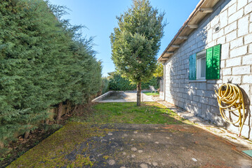 Garden terrace with natural grass bordered by stone curbs, a built-in barbecue, and a chill-out area