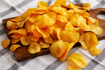 Homemade Flavored Cheese Potato Chips on a Wooden Board, side view.
