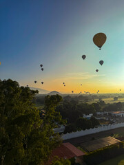 Spectacular sunrise aerial view of hot air balloons flying over the ancient Teotihuacan pyramids, a famous landmark and travel destination in Mexico.
