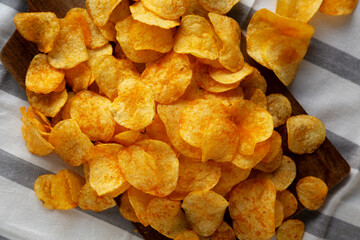 Homemade Flavored Cheese Potato Chips on a Wooden Board, top view.