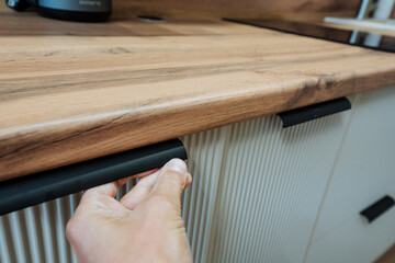 This modern kitchen features stylish cabinet handles and a highquality wooden countertop, creating...