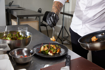 Closeup of chef hands preparing shrimp salad in a luxury restaurant kitchen