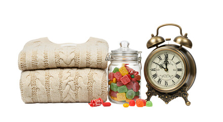 Stacked knitted sweaters with heart patterns next to a glass jar of colorful gummy candies and a vintage alarm clock on white background, perfect for cozy lifestyle themes