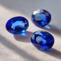 Three oval-cut blue gemstones on a light surface