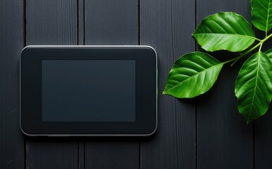 Black tablet device green leaves dark wood screen