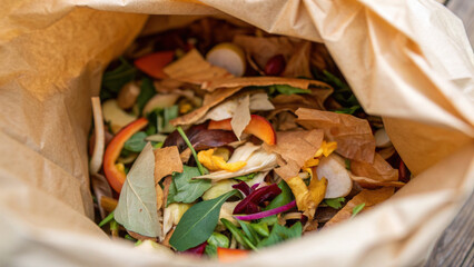 Top view of compostable paper bag full of organic food waste. This sustainable waste management practice involves recycling kitchen scraps and leftover vegetable peels for compost