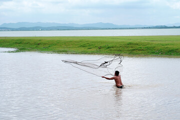 Fisherman holding fish net to caught fish in the lake net at the coast of Ban Tha rit campground as know as New Zealand in Thailand in Lopburi Province, Thailand.