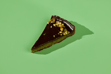 Indulgent and Decadent Slice of Chocolate Cake Decorated with Pistachio on a Green Backdrop