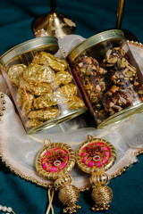 Festive sweets presentation: golden chocolates and nut-seed treats in clear jars, adorned with decorative ornaments. Gifting essentials for special occasions.