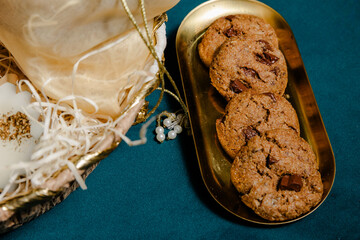 Delicious chocolate chip cookies served on an elegant golden tray with a decorative gift box for a touch of luxury and indulgence. Enjoy the sweet treat!