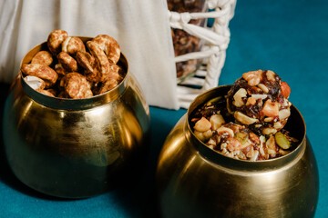 Nutritious nuts, seeds, and date balls in brass bowls offer a healthy snack choice. Golden hues add...