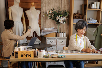 two Asian women working in their clothing design studio.
