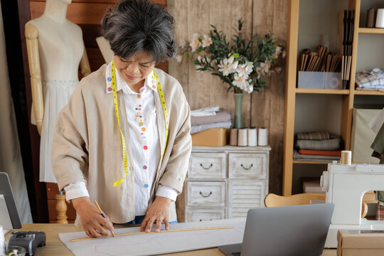 Asian woman designing clothes in her studio.