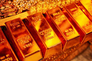 Stack of gold bars with the number 999.99 and Net WT 1000 g Gold bars and gold jewelry background. Financial concepts.
