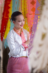 Woman in traditional attire smiles while surrounded by colorful, decorative flags, creating festive and cultural atmosphere