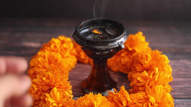 Mexican offering with hand holding a burning and smoky incense called "Incienso de copal" on altar for Celebration of Mexico's Day of the Dead in Latin America