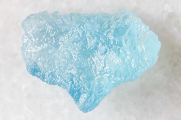 sample of raw aquamarine mineral on white marble