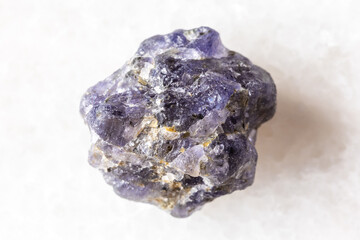 sample of rough iolite mineral on white marble