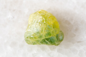 rough yellow green sapphire mineral on white