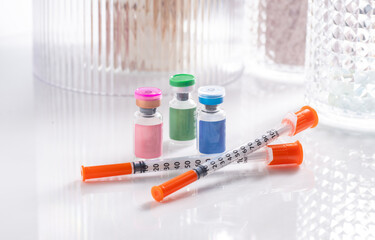 Close up of Vials with Various Injectable Compounds Next to Syringes