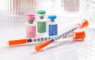 Close up of Vials with Various Injectable Compounds Next to Syringes