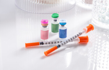 Close up of Vials with Various Injectable Compounds Next to Syringes