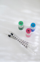 Close up of Vials with Various Injectable Compounds Next to Syringes