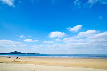 Obraz premium Blue Sky Over Sandy Coastal Beach with Ocean Horizon