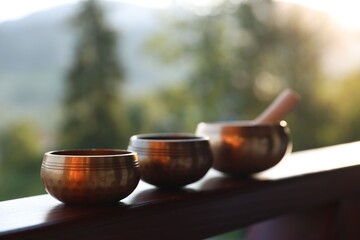 Tibetan singing bowls with mallet on handrail outdoors, closeup