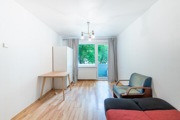 Minimalist Small Living Room Interior With Bed, Wooden Desk, and Natural Light
