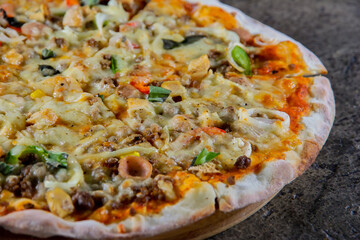 Close Up of Hot Pizza with Cheese and Toppings on Wooden Plate