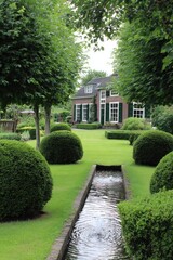 Obraz premium A meticulously landscaped garden with a water feature, showcasing neatly trimmed hedges and lush greenery surrounding a charming house.