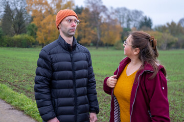 Older mother and adult son argue in autumn park, emotional distance, family conflict, generational...
