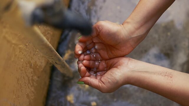 Water Dropping on Woman&rsquo;s Cupped Palms from Tap