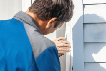 A man closely examining a wooden door, checking for damage or wear. The setting suggests home maintenance or renovation work.