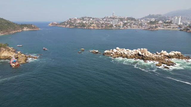 A horizontal drone pan showcasing Roqueta Island and Caleta Beach in Acapulco, revealing the landscape and the effects of Hurricane Otis