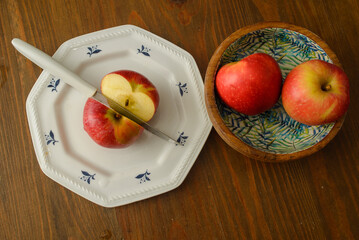 A knife that cut a red apple on a white plate