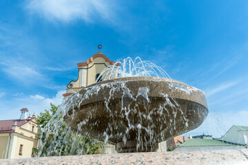 Fountain in front of historic building. Elegant fountain with flowing water in front of old stone architecture under clear blue sky in charming European town.