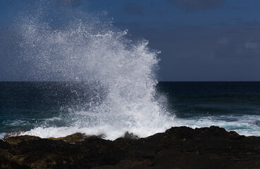 Gran Canaria, north west coast around natural swimming pools Salinas de Agaete, waves breaking against old eroded dark lava platform