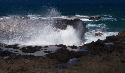 Fototapeta premium Gran Canaria, north west coast around natural swimming pools Salinas de Agaete, waves breaking against old eroded dark lava platform 
