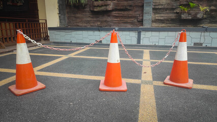 Three Orange Traffic Cones Connected by Chain