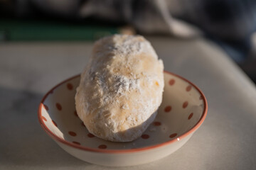 a qurabiya cookies rests in a red polka dot bowl, bathed in soft natural light.
