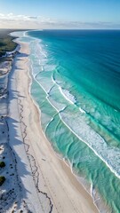 Aerial view of a pristine white sandy beach with turquoise ocean waves and foam, showing the beautiful coastline and symbolizing vacation, travel, and the beauty of nature.

