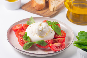 Traditional Italian burrata cheese with salad of delicious cherry tomato, basil leaves and olive oil.