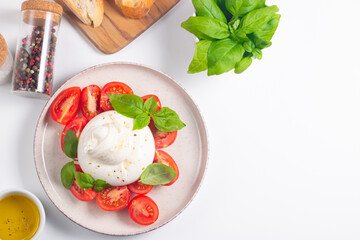 Traditional Italian burrata cheese with salad of delicious cherry tomato, basil leaves and olive oil.