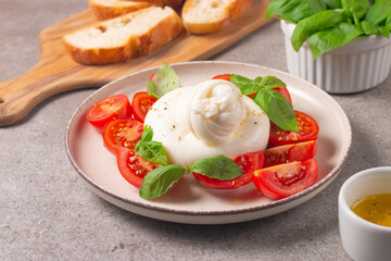 Traditional Italian burrata cheese with salad of delicious cherry tomato, basil leaves and olive oil.